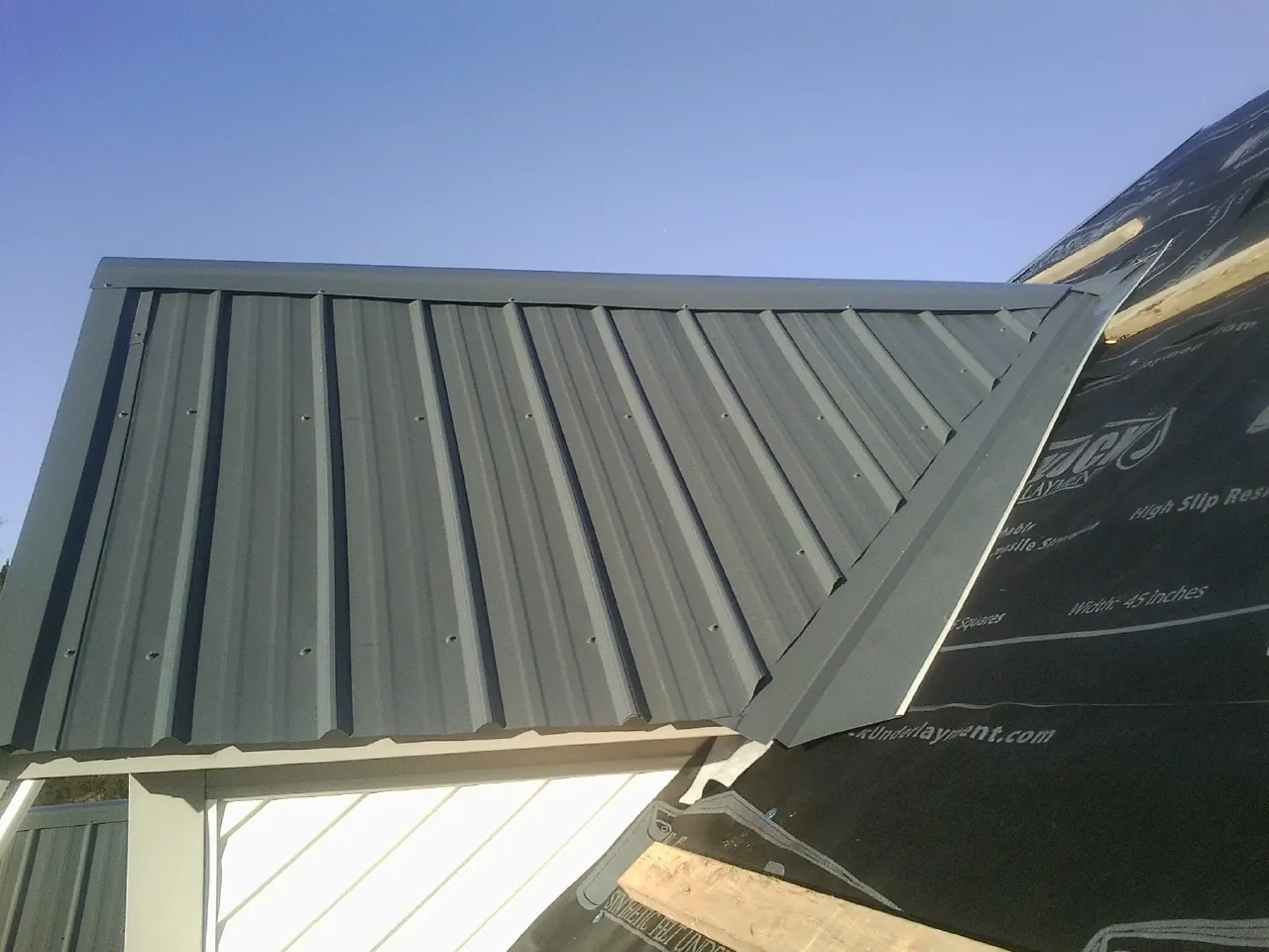 Gray metal roof panels going on over a garage gable in Trenton